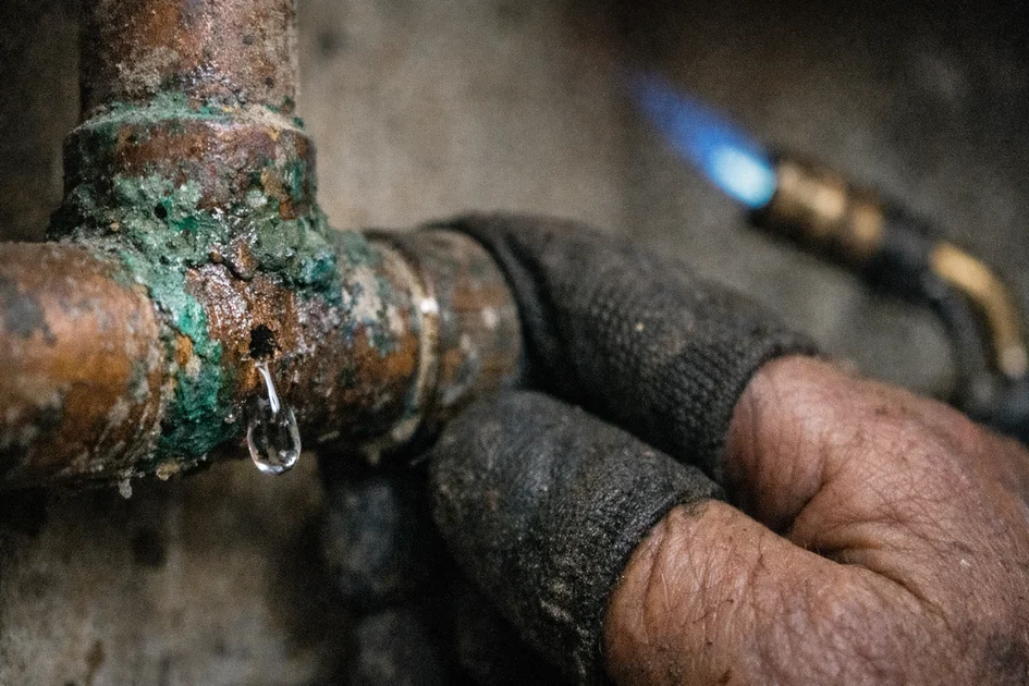 Photos réaliste d'un plombier réparant une fuite tuyau cuivre sous un évier de cuisine
