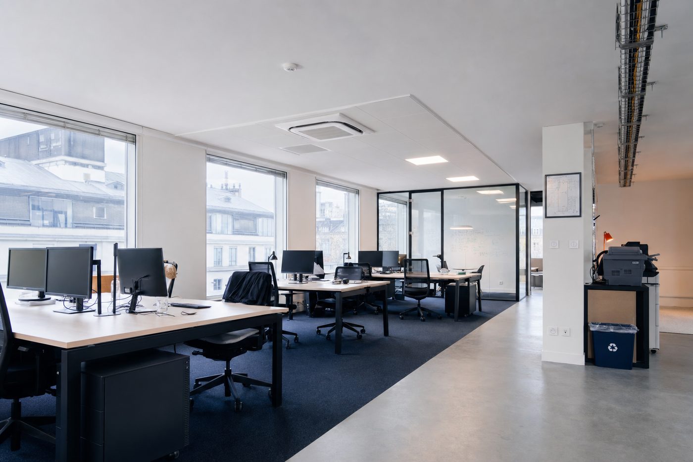 Plateau de bureaux en open space avec une cassette de climatisation au plafond au-dessus des postes de travail